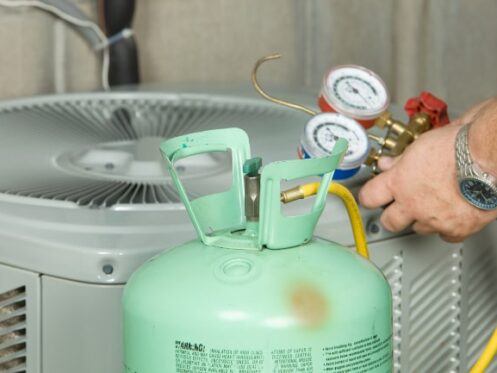 Technician re-charging a condenser unit with new refrigerant